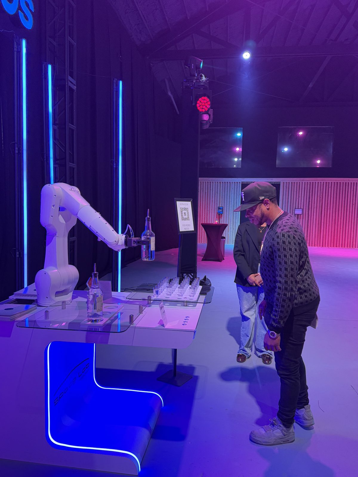 The RoboBar robotic bartender mixing drinks under kinetic lighting at a live event
